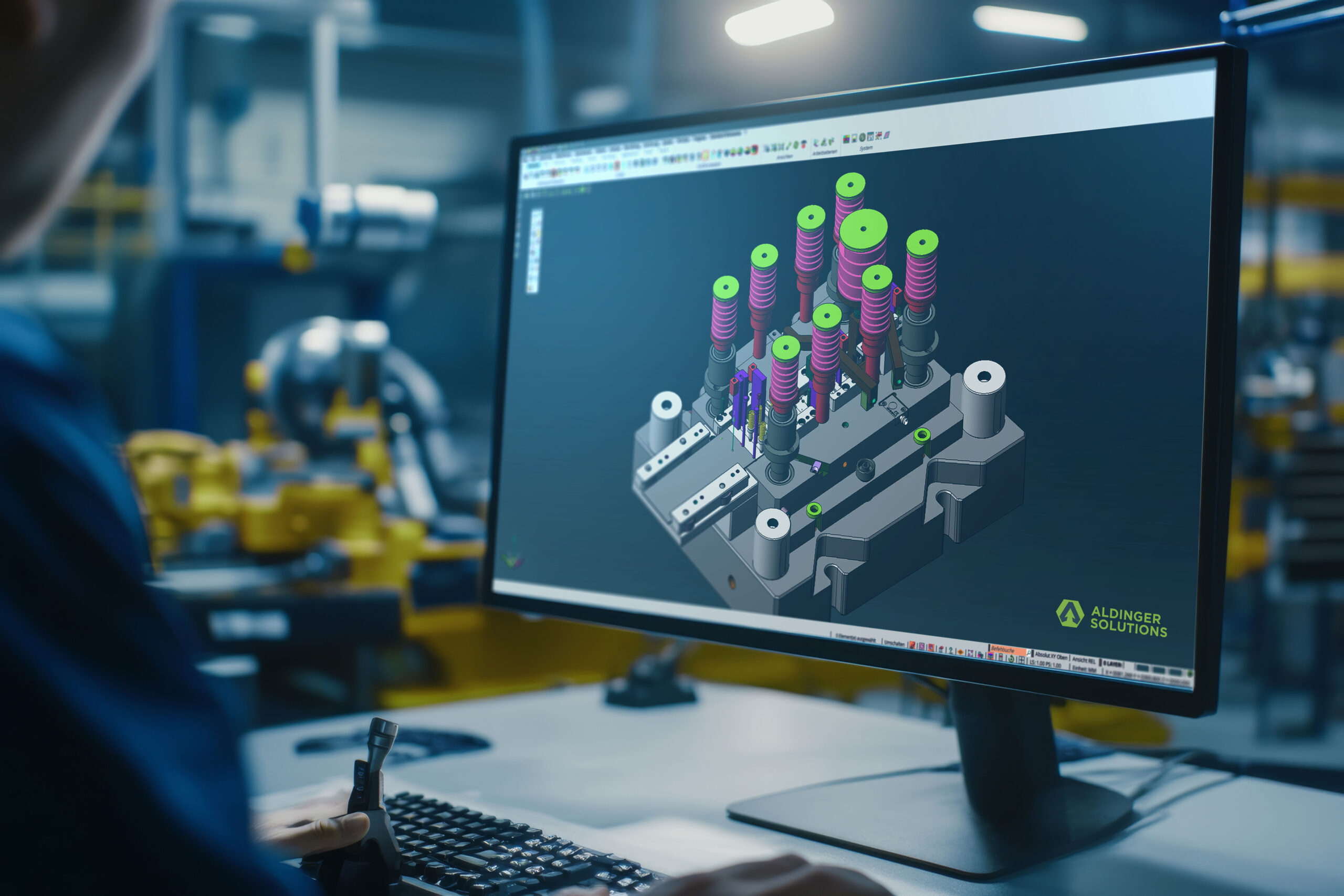 CAD-Konstruktion eines Stanzwerkzeugs auf Monitor mit Aldinger Solutions Logo in einer modernen Industrieumgebung